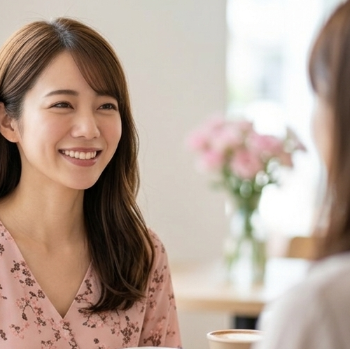 友人と笑顔で会話する、穏やかで優しい印象の女性。婚活プロフィールの自己PRで人から言われる客観的な性格を書くコツを表す写真アイコン - はなまるプロ